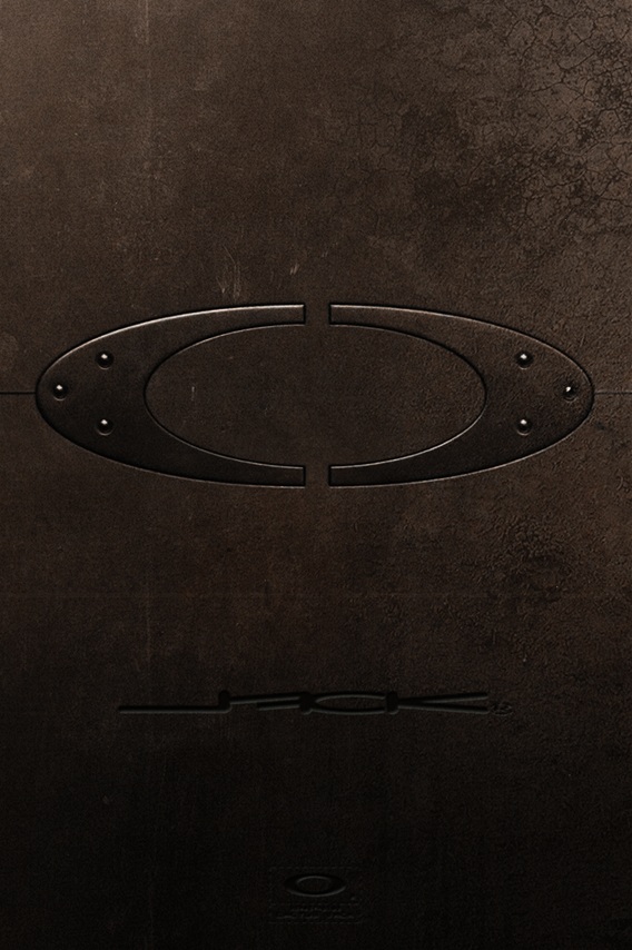 Logo Oakley gravé en relief sur un matériau texturé sombre, montrant le design ovale iconique 'O' avec des éléments latéraux distinctifs sur fond noir