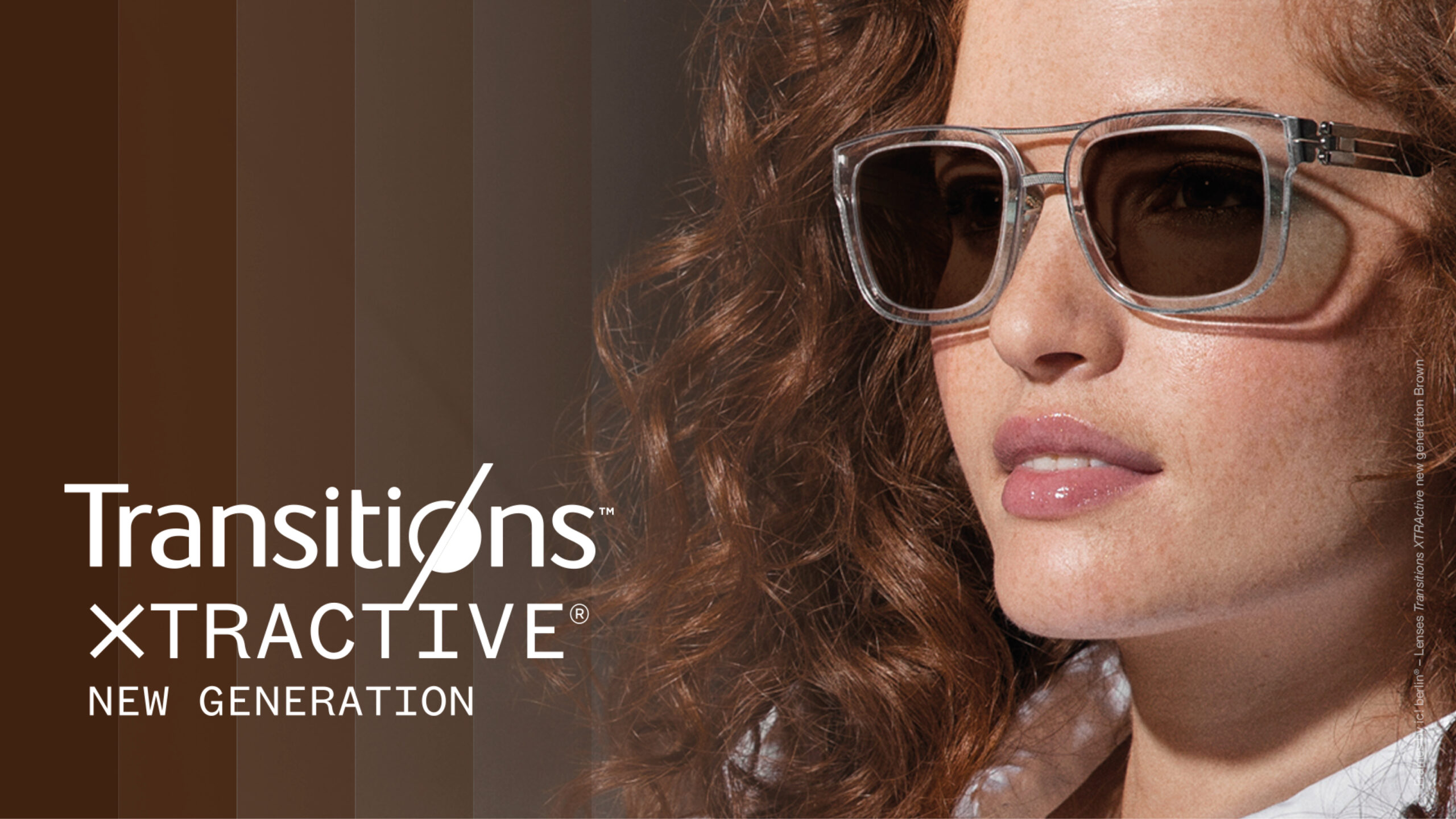 Woman wearing clear-framed sunglasses with brown tinted lenses, with text displaying 'Transitions XTRACTIVE New Generation' eyewear branding.