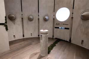 Oakley Meta collaboration experience room with circular porthole windows, natural elements, suspended pendant lights, and Oakley/Meta branding displaying AI wearable technology.