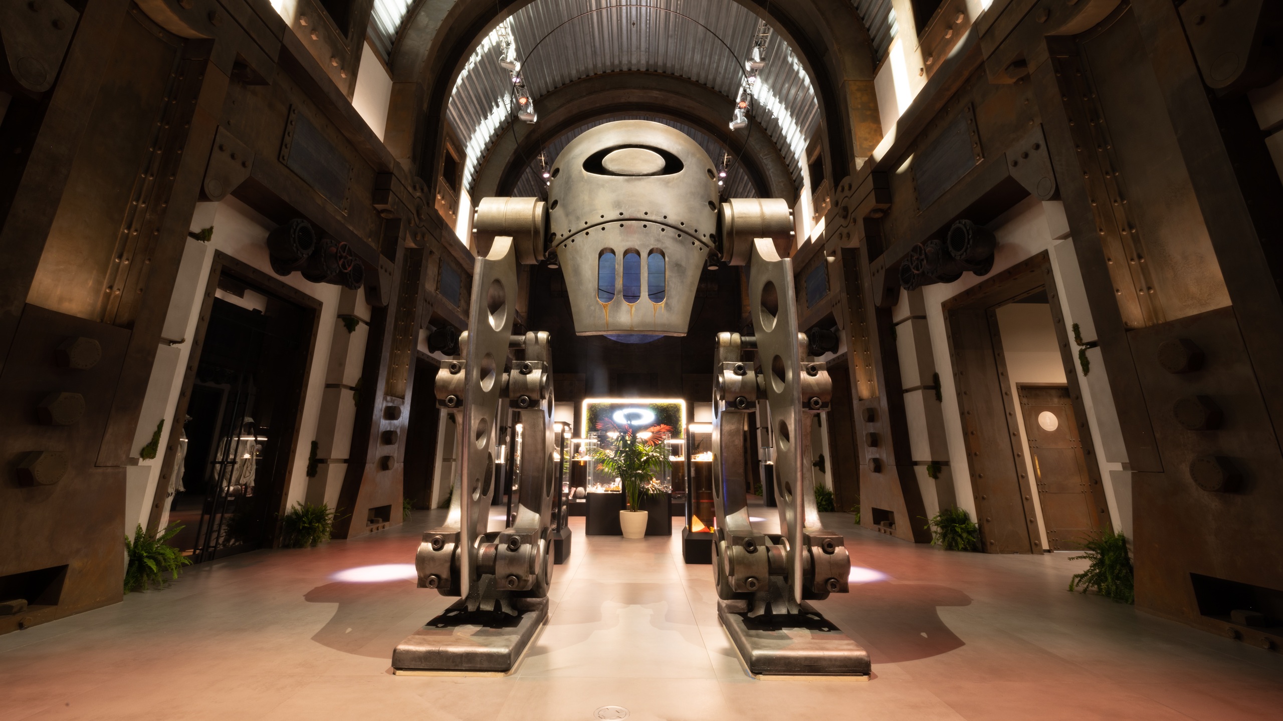 Futuristic Oakley headquarters entrance featuring a large metallic robot-like sculpture with the Oakley logo, industrial design elements, and dramatic lighting in an atrium setting.