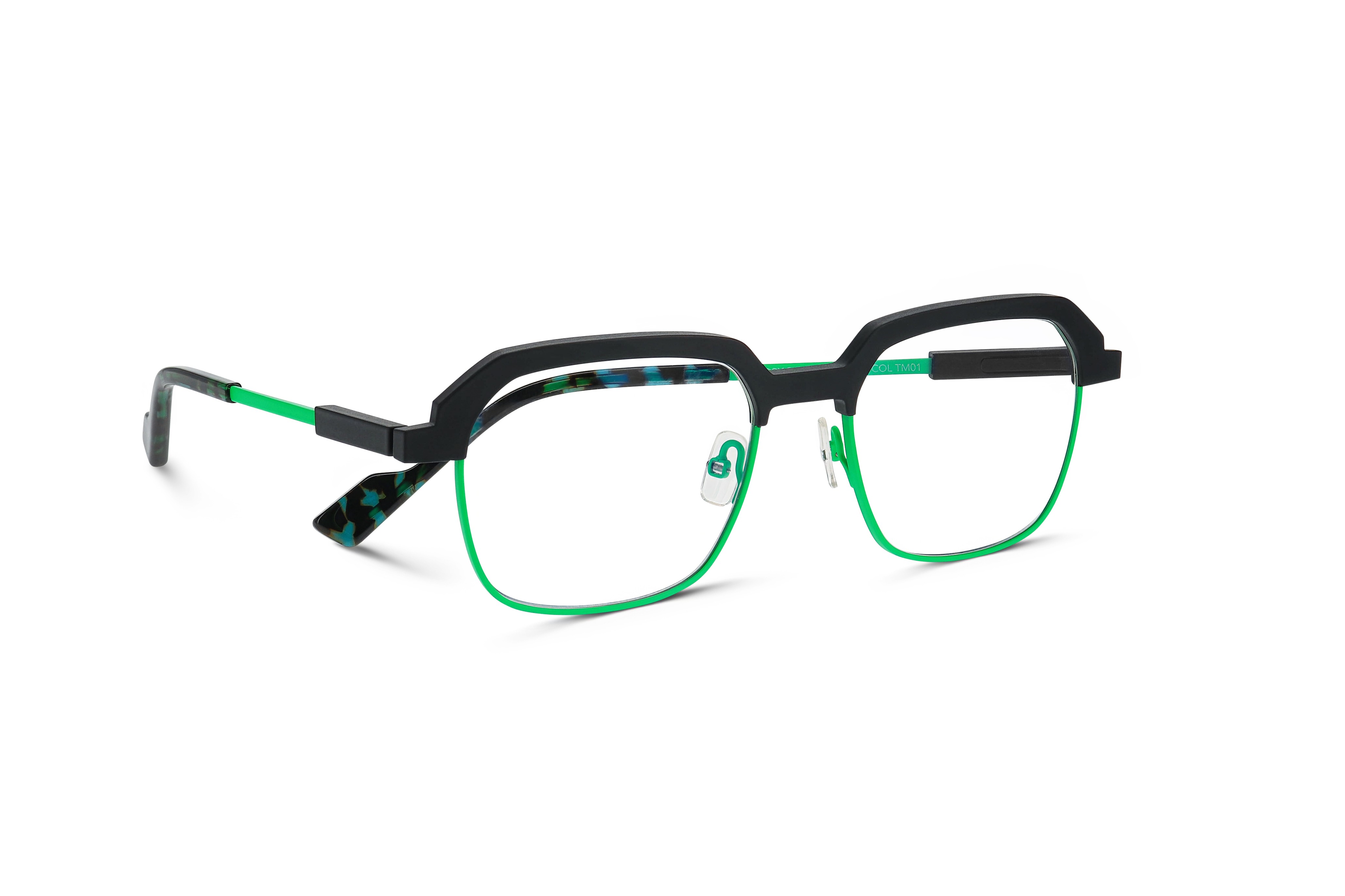 Gros plan sur les lunettes FACTORY de Face à Face, combinant une monture métallique noire sur la partie supérieure avec des cercles en fil fluorescent vert et des branches à motif, évoquant un design d’inspiration industrielle.
