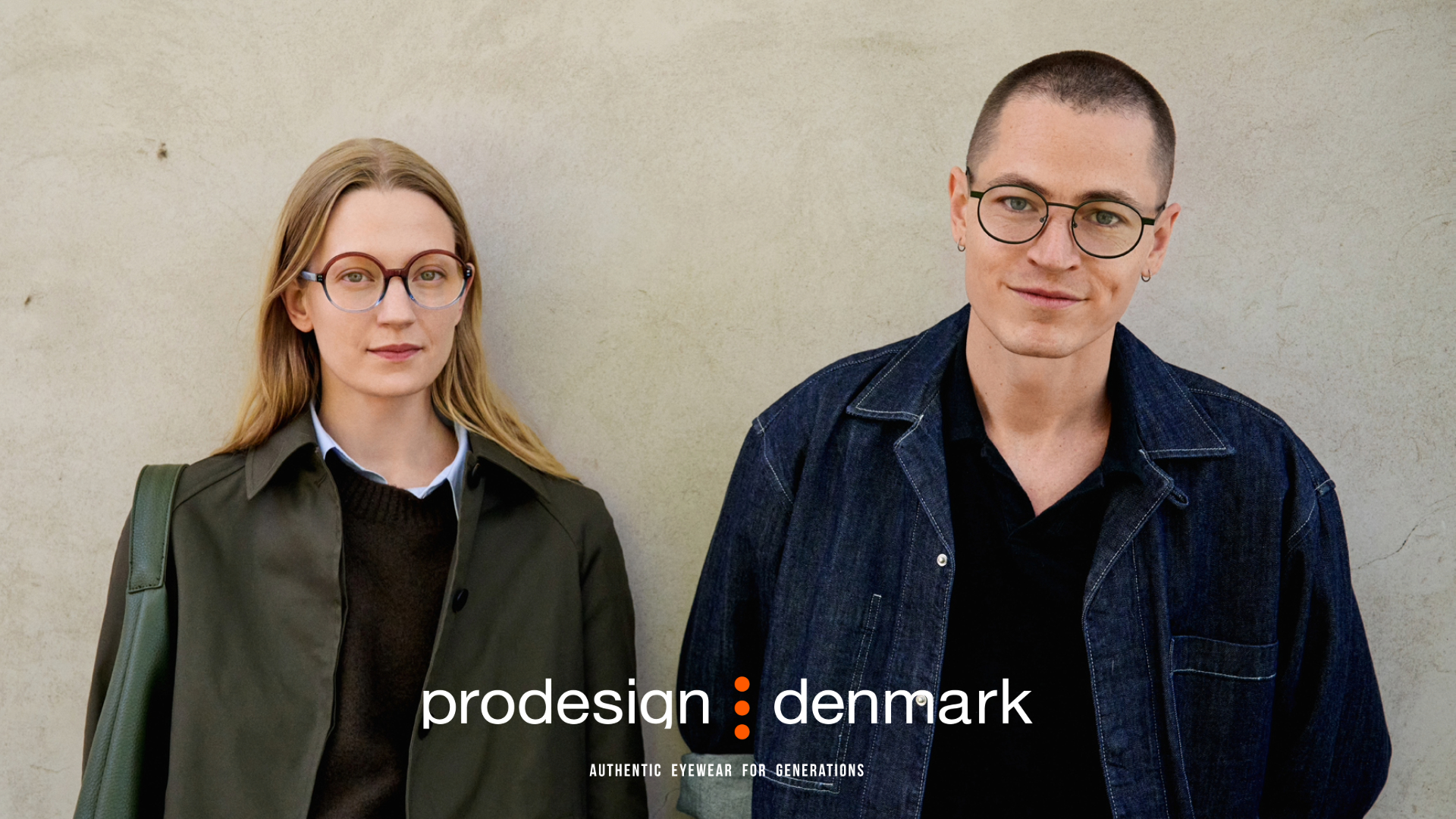 Two people wearing Prodesign Denmark eyewear standing against a concrete wall. On the left, a woman with blonde hair wearing round tortoiseshell glasses and an olive green jacket. On the right, a person with short hair wearing round black-framed glasses and a dark denim jacket. The Prodesign Denmark logo and tagline 'Authentic Eyewear for Generations' appears at the bottom.