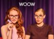 Two young women modeling WOOW eyewear against a purple curtain backdrop. The woman on the left has long red hair and wears tortoiseshell-patterned glasses while holding a purple card, dressed in a pink top. The woman on the right has blonde hair in a bun and wears round glasses with colorful accents, dressed in a brown sweater. The WOOW brand logo appears prominently at the top