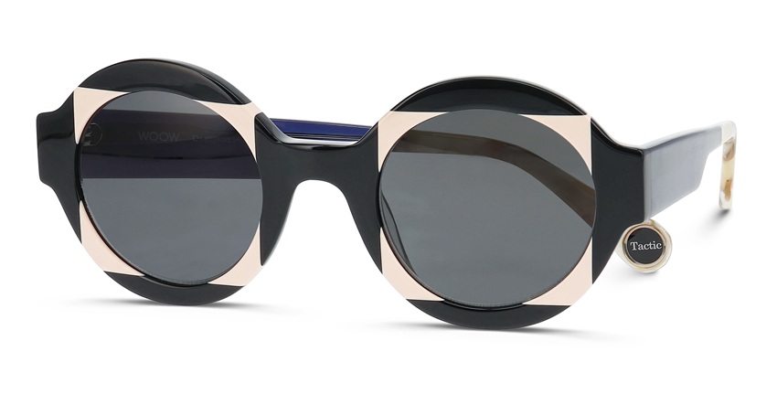 Lunettes de soleil WOOW "Super Tactic" présentant un design géométrique audacieux avec des blocs de couleur noire et beige, des verres gris foncé, et une forme de monture angulaire distinctive avec la marque "Tactic" visible sur la branche.