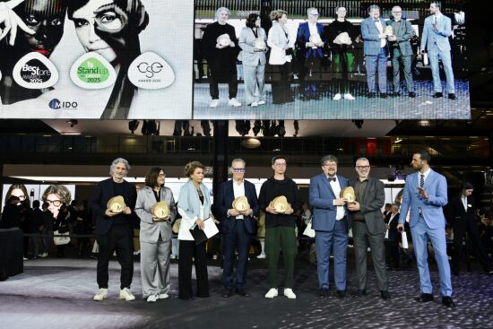 MIDO awards ceremony showing a group of award winners standing on stage holding golden trophy awards, with a large screen behind them displaying the event branding including Best Store Award, Stand Up For Green 2025, CSE Award 2025, and MIDO logos alongside images of eyewear models.