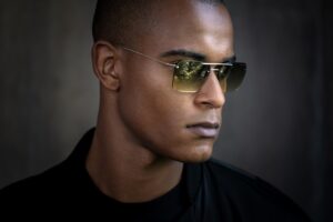 Portrait professionnel d'un homme portant des lunettes de soleil Blackfin Aero Loop Infinity avec verres dégradés verts, démontrant l'esthétique minimaliste audacieuse et la personnalité distinctive du design sans monture en titane
