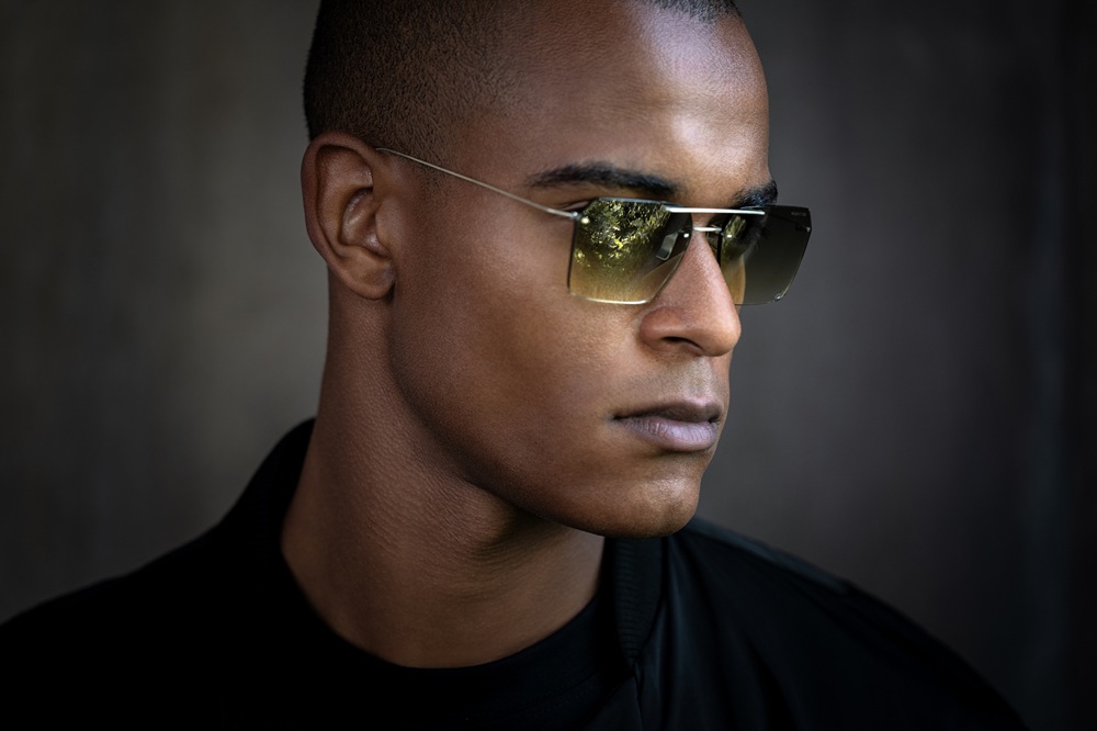 Professional portrait of a man wearing Blackfin Aero Loop Infinity sunglasses with green gradient lenses, demonstrating the bold minimalist aesthetic and distinctive personality of the rimless titanium eyewear design