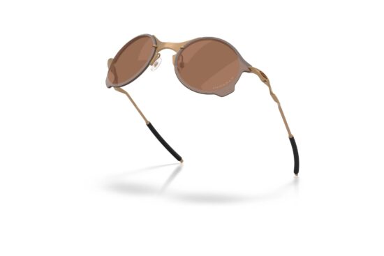 Oakley Tailend TI sunglasses in matte gold with Prizm Tungsten lenses, displayed at an angle to highlight the featherlight titanium frame.