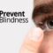 Gros plan de l'œil d'une personne et de son doigt alors qu'elle insère ou retire une lentille de contact, avec le logo de Prevent Blindness (présentant un design circulaire aux tons bleus, verts et jaunes) affiché de manière proéminente dans le coin supérieur gauche de l'image.