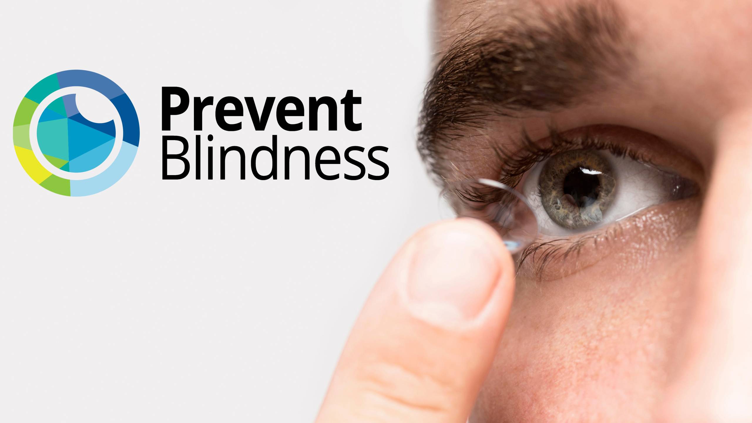 Close-up of a person's eye and finger as they insert or remove a contact lens, with the Prevent Blindness logo (featuring a circular design in blue, green, and yellow tones) displayed prominently in the upper left corner of the image.
