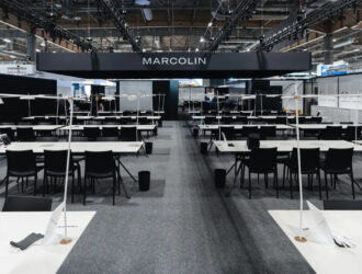 Marcolin exhibition booth at SILMO 2025 Paris featuring modern minimalist design with white display tables and black chairs in Hall 6