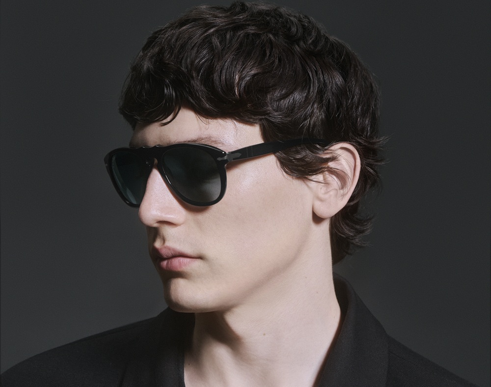 Le mannequin Filipe Nieves de profil portant les lunettes de soleil Persol Total Black Arrow avec des vêtements noirs, mettant en valeur le design sculptural de la monture et l'esthétique cinématographique