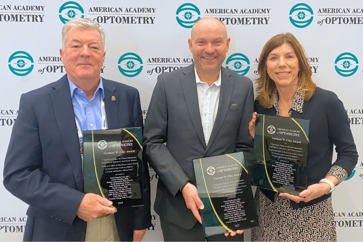 Three researchers holding Garland W. Clay Award plaques at American Academy of Optometry ceremony