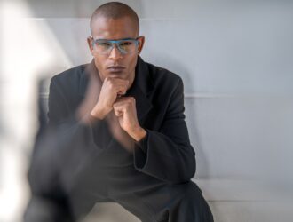 Man wearing blue square Blackfin titanium eyeglasses in black suit