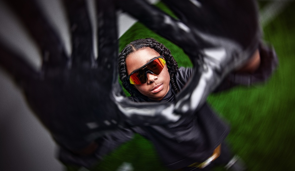 Young athlete wearing Oakley Resistor Sweep sunglasses reflected in a football helmet visor