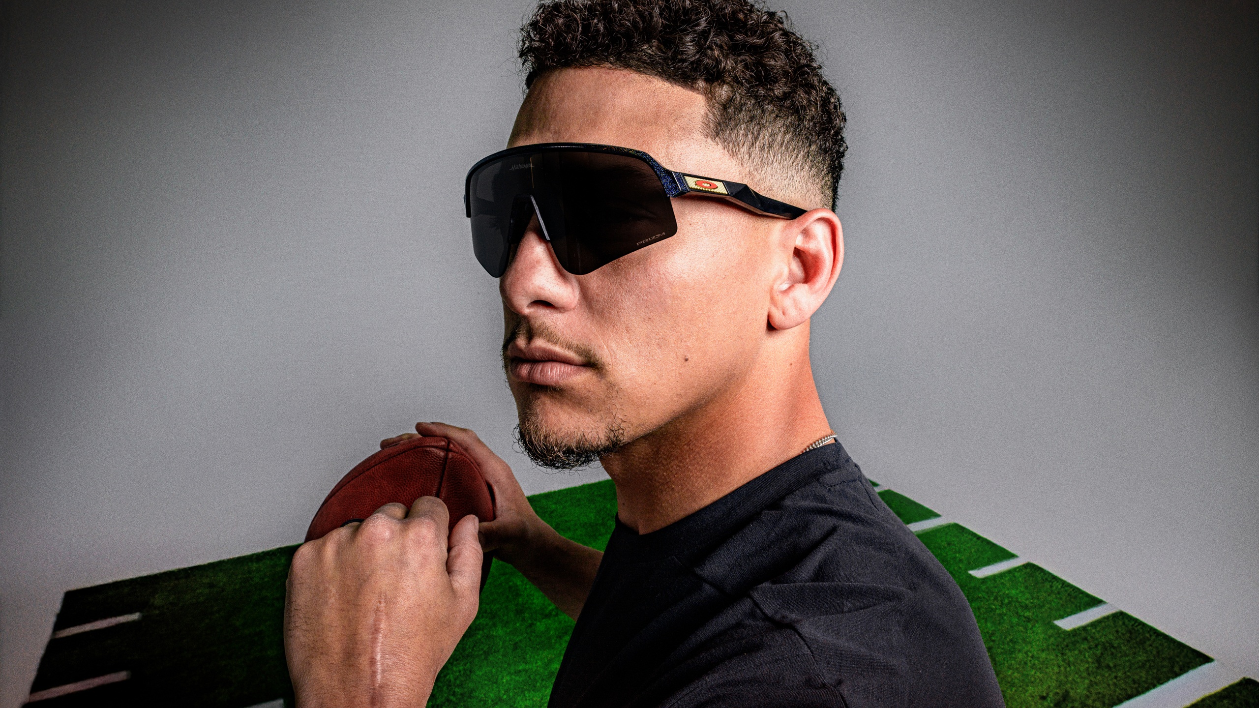 Patrick Mahomes portant des lunettes Oakley Sutro Lite Sweep tout en tenant un ballon de football