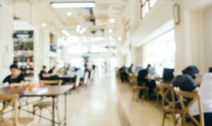 Blurred interior of a bright, modern library with people studying at wooden tables
