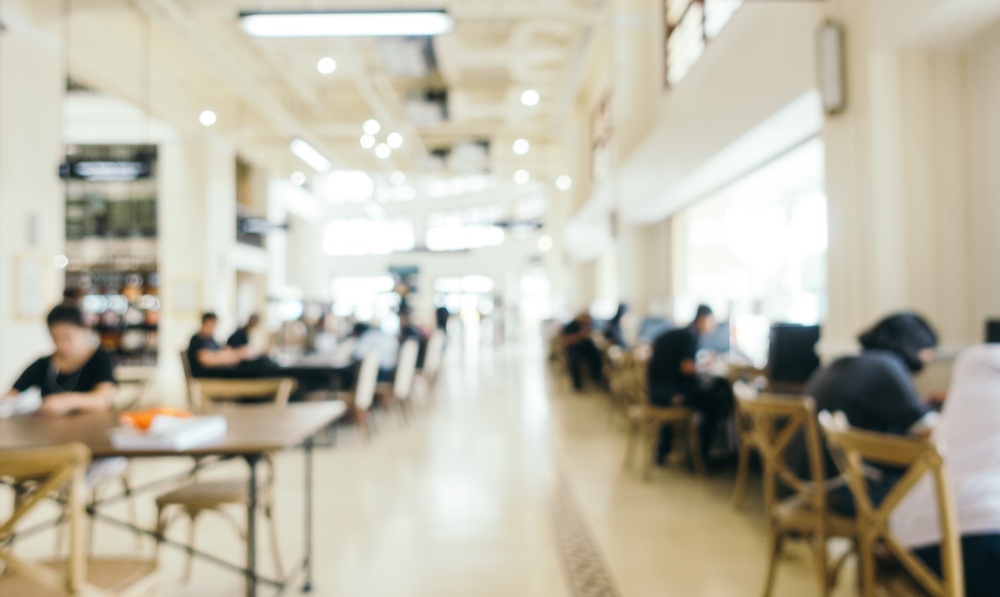 Blurred interior of a bright, modern library with people studying at wooden tables