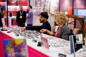 Professionnels de l'optique examinant une collection de lunettes sur un stand de l'exposition 100% Optical