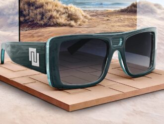 Lunettes de soleil INVU ultra polarisées turquoise sur présentoir en bois avec fond de plage