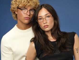 Two young models wearing GUESS JEANS eyeglasses against blue background