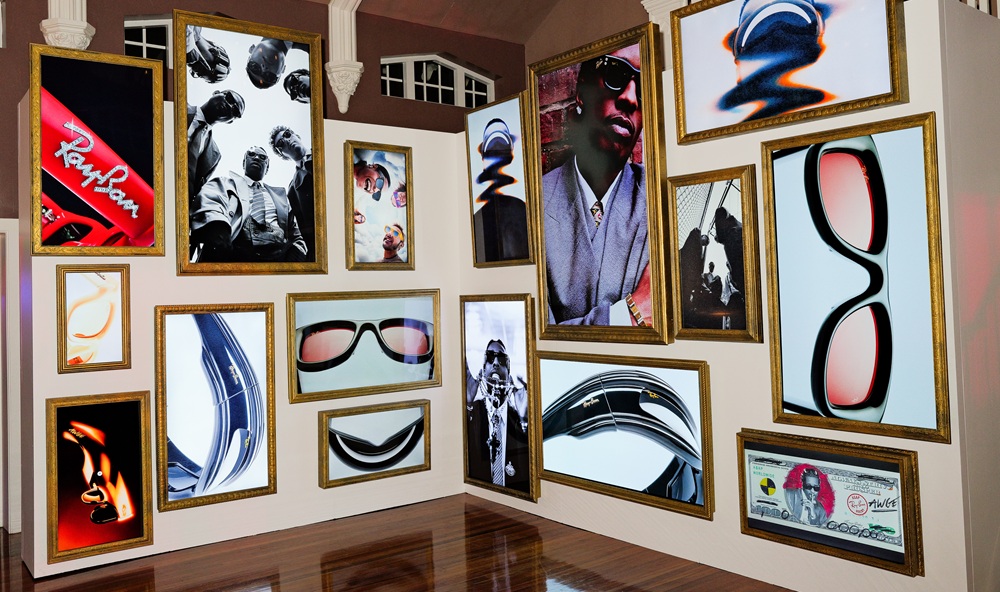 Mur de galerie exposant la collection Ray-Ban à travers des photographies artistiques encadrées d'or et des visuels de campagne