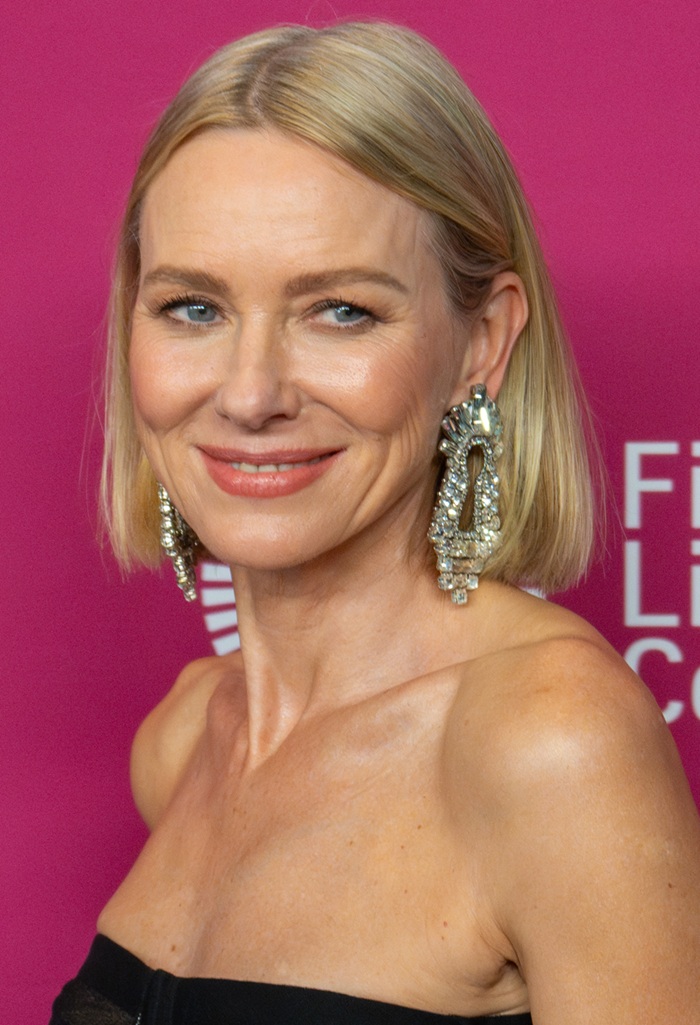 portrait de Naomi Watts lors d'un événement de festival de cinéma, portant des bijoux élégants sur fond rose