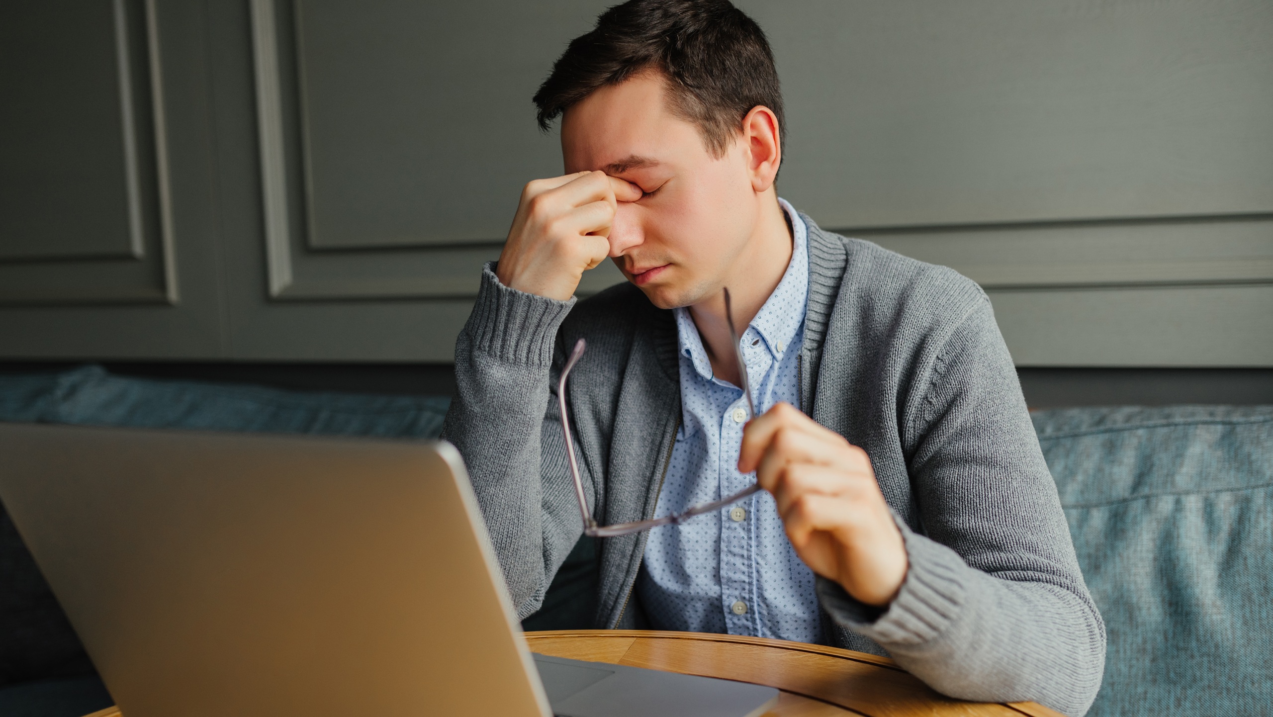 Man experiencing eye strain while working on laptop, rubbing his eyes in discomfort