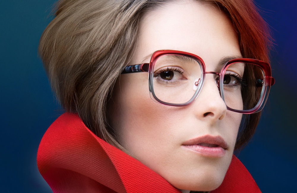 Femme aux cheveux courts bruns portant des lunettes carrées dégradé rouge et bleu et col rouge