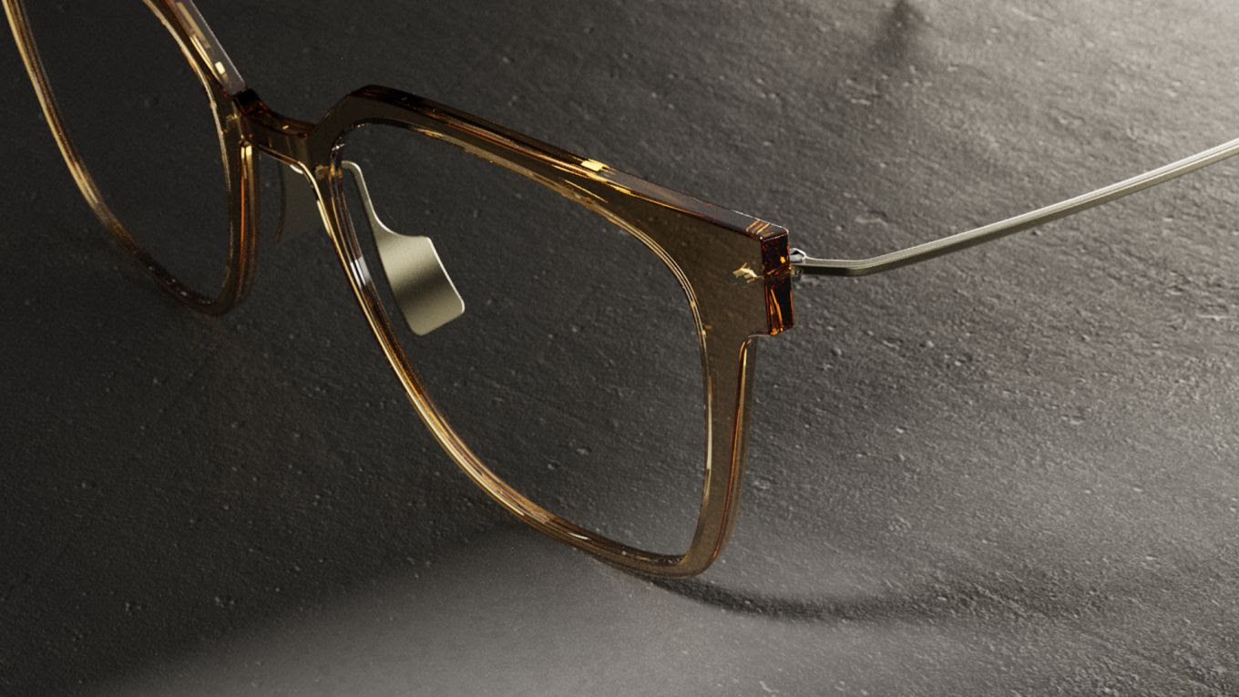 Close-up of Blackfin Vitra eyewear featuring a transparent amber VitraCore™ front and slim titanium temples on a textured stone surface.