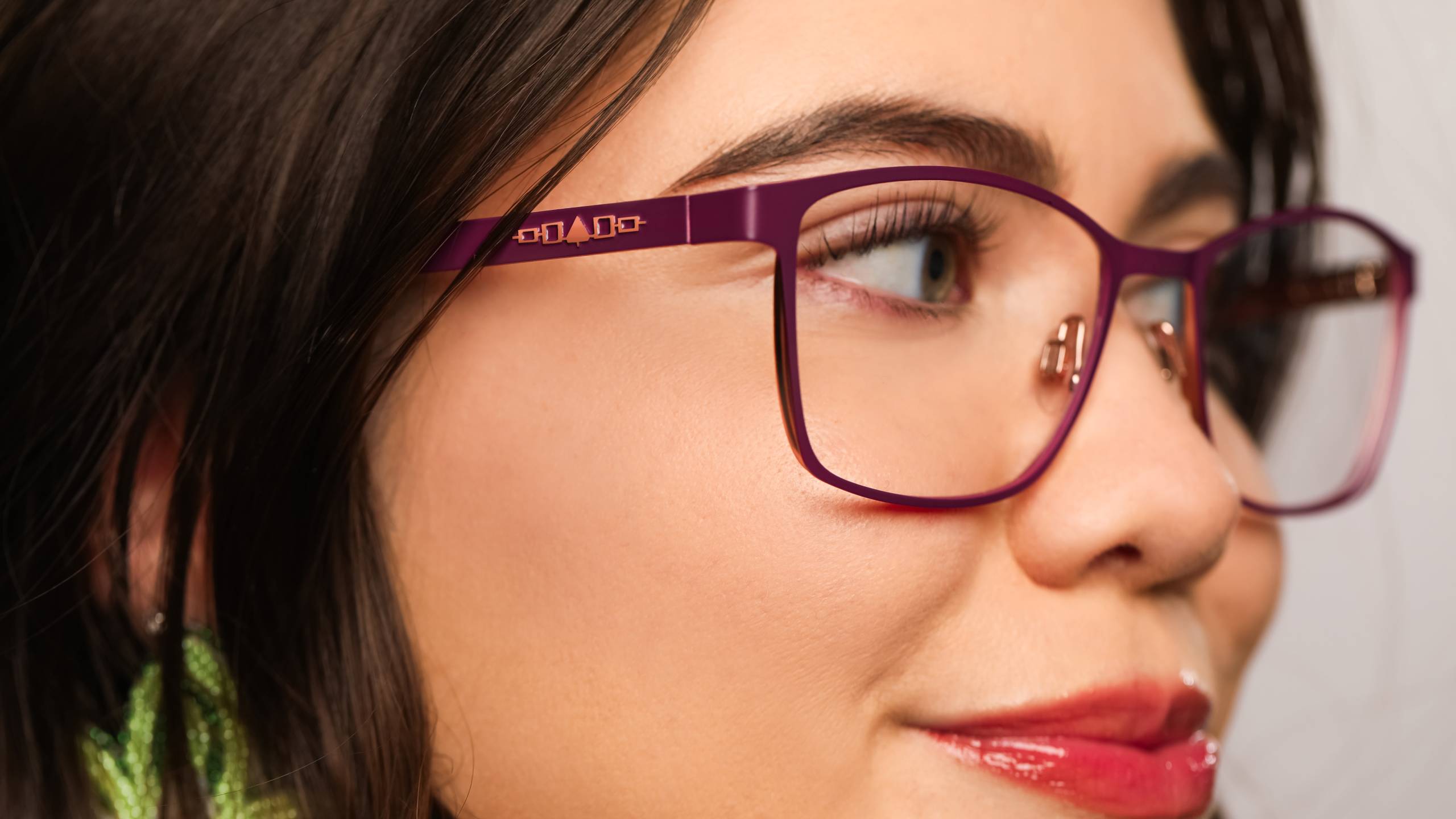 Close-up of a woman wearing purple Ió:ken Designs eyeglasses featuring Indigenous geometric pattern details on the temple