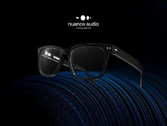 Nuance Audio hearing aid glasses in black frame displayed on blue acoustic soundwave surface against dark background