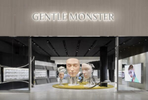 Façade d'entrée de Gentle Monster à Yorkdale avec l'enseigne lumineuse de la marque, des installations de têtes robotiques et un tapis circulaire jaune accueillant les visiteurs.