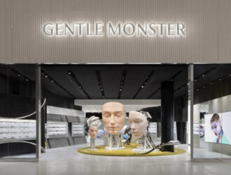 Façade d'entrée de Gentle Monster à Yorkdale avec l'enseigne lumineuse de la marque, des installations de têtes robotiques et un tapis circulaire jaune accueillant les visiteurs.