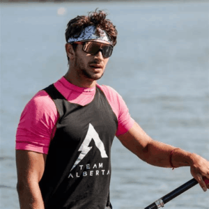 Elite sprint canoeist Nikita Ciudin wearing sunglasses and Team Alberta gear while paddling on the water