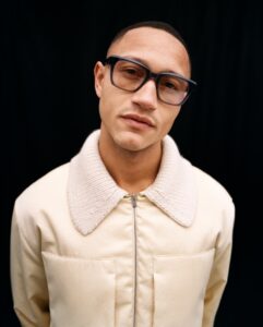 Mannequin portant des lunettes en acétate Ørgreen Optics avec teinte légère sur fond noir, vêtu d'une veste crème à col en mouton retourné