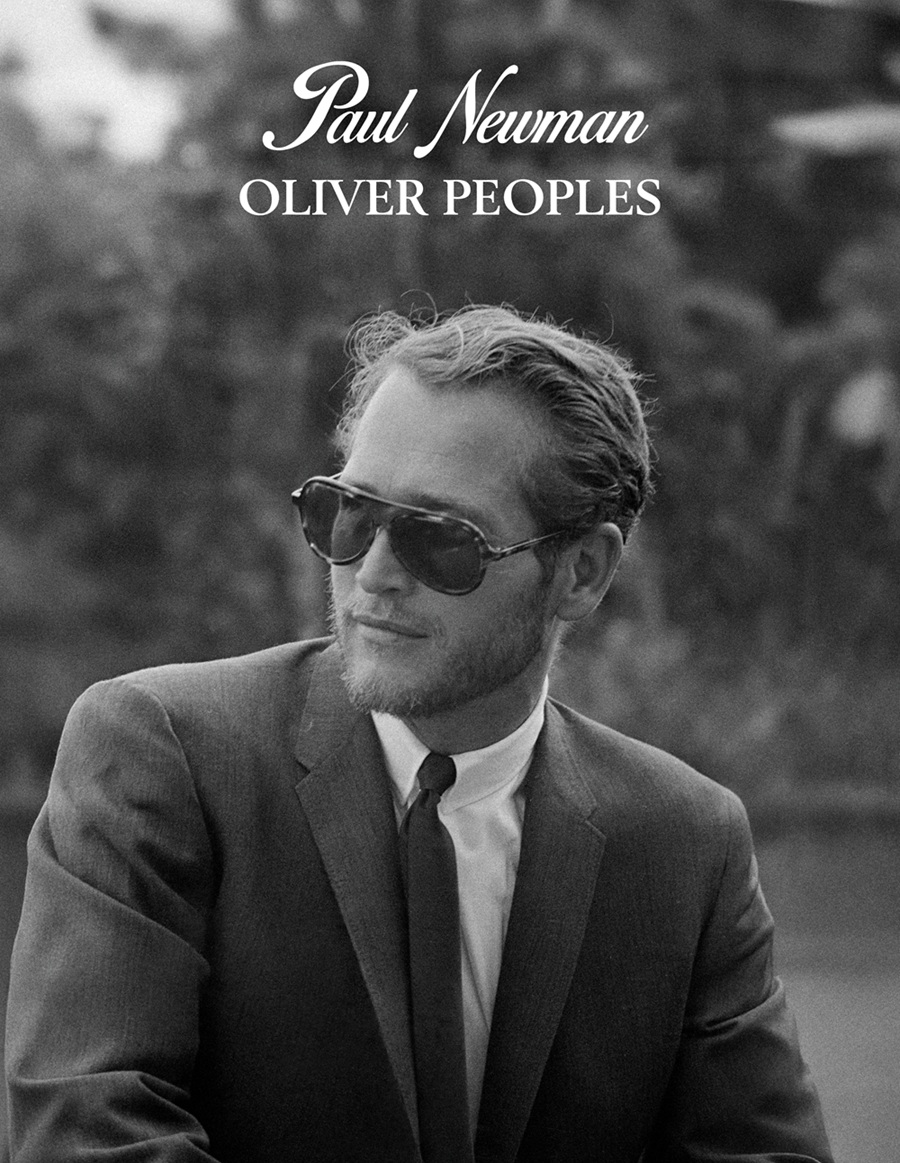 A classic black-and-white portrait of actor Paul Newman wearing a suit, tie, and his signature teardrop-shaped aviator sunglasses.
