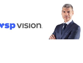 Nicola Zotta, président de l'activité lunetterie chez VSP Vision, debout les bras croisés à côté du logo VSP Vision