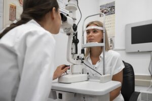 Professionnelle des soins oculaires effectuant un examen des yeux sur une patiente à l'aide d'une lampe à fente dans un environnement clinique