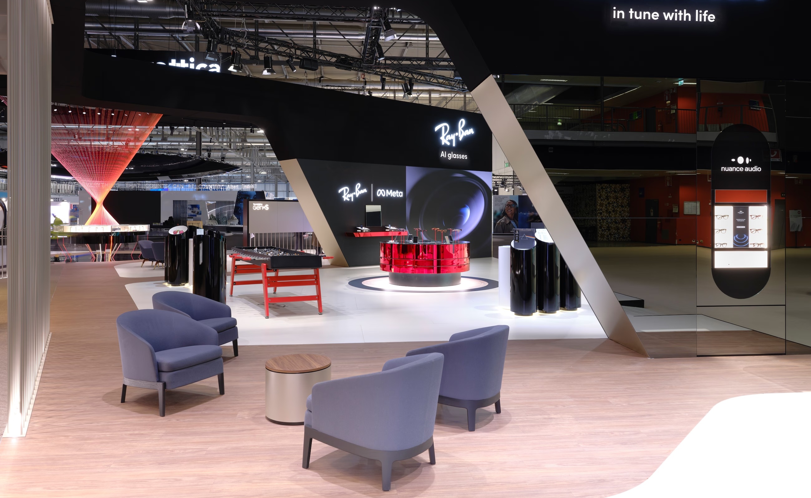 Vue intérieure de l'exposition EssilorLuxottica montrant un espace dédié aux lunettes Ray-Ban Meta AI et une borne Nuance Audio dans un espace lounge.