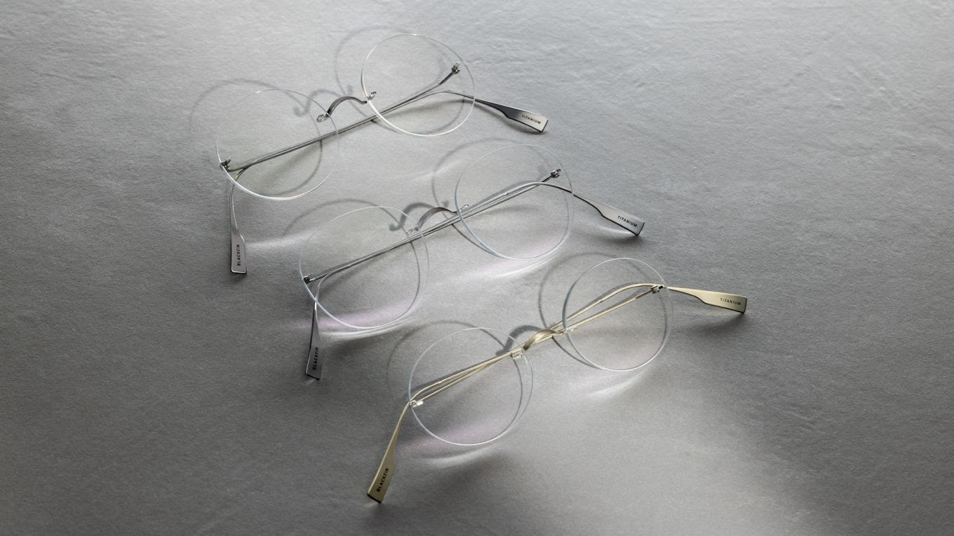 Trois paires de lunettes sans monture Blackfin Aero Infinity en titane posées sur une surface grise, projetant de douces ombres circulaires.