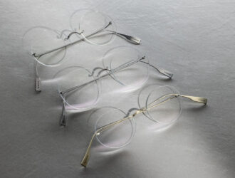 Three Blackfin Aero Infinity rimless titanium eyeglasses laid on a grey surface, casting soft circular shadows