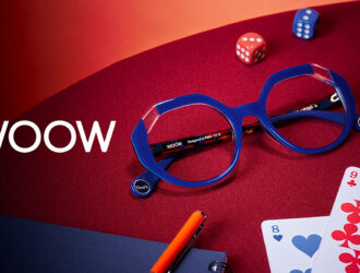 WOOW brand campaign image showing Times Up 2 optical frames in cobalt blue on a red surface, surrounded by playing cards, dice, and a pen