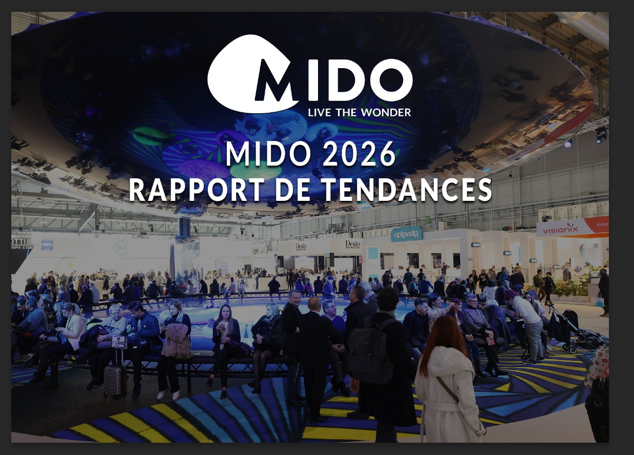 Grand hall d'exposition au salon professionnel de lunetterie MIDO 2026 avec des visiteurs rassemblés autour d'une scène circulaire éclairée en bleu. Le logo MIDO avec le slogan 'Live the Wonder' et le texte 'MIDO 2026 RAPPORT DE TENDANCES' superposés sur la scène. Stands d'exposition de marques comme Optovisol, Desio et Visionix visibles en arrière-plan.
