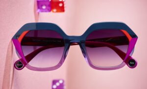 Lunettes de soleil WOOW Super Ace 2 à monture acétate géométrique tricolore bleu marine, fuchsia et lilas, sur fond rose avec des dés colorés