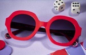 WOOW Super Score 2 sunglasses in bold red with rounded frames, styled with dice on a purple background
