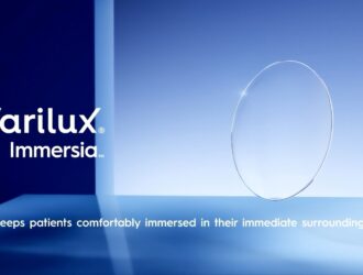 Un verre de lunettes Varilux Immersia flottant avec un motif hexagonal bleu, sur un fond minimaliste bleu avec le logo Essilor en haut à droite.