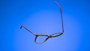 ReForm Eyewear par Mondottica — montures optiques noires flexibles avec des embouts de branches rouges sur fond bleu