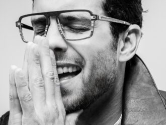 Man wearing J.F. Rey Carbonwood frames, laughing, black and white portrait