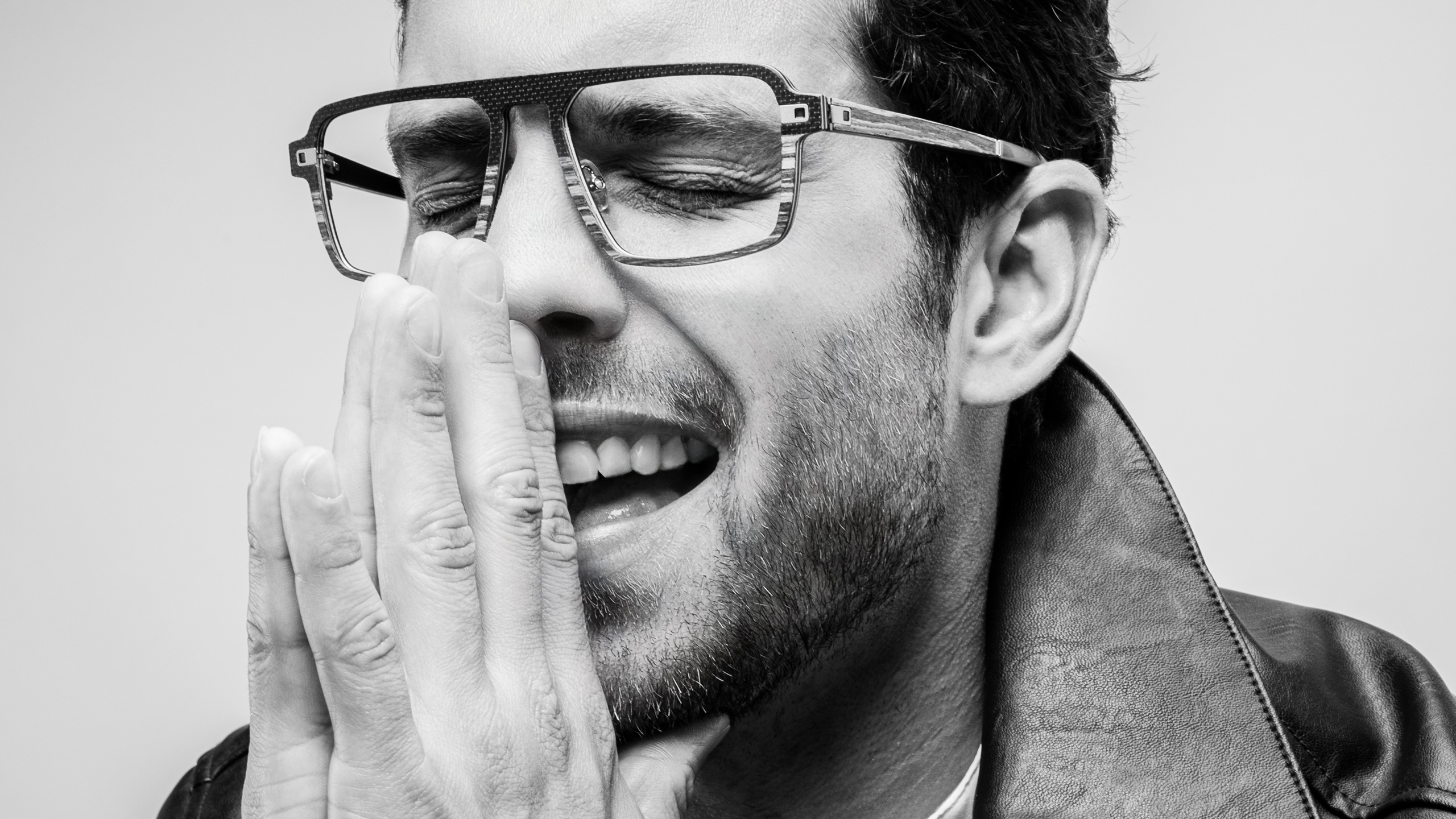 Man wearing J.F. Rey Carbonwood frames, laughing, black and white portrait
